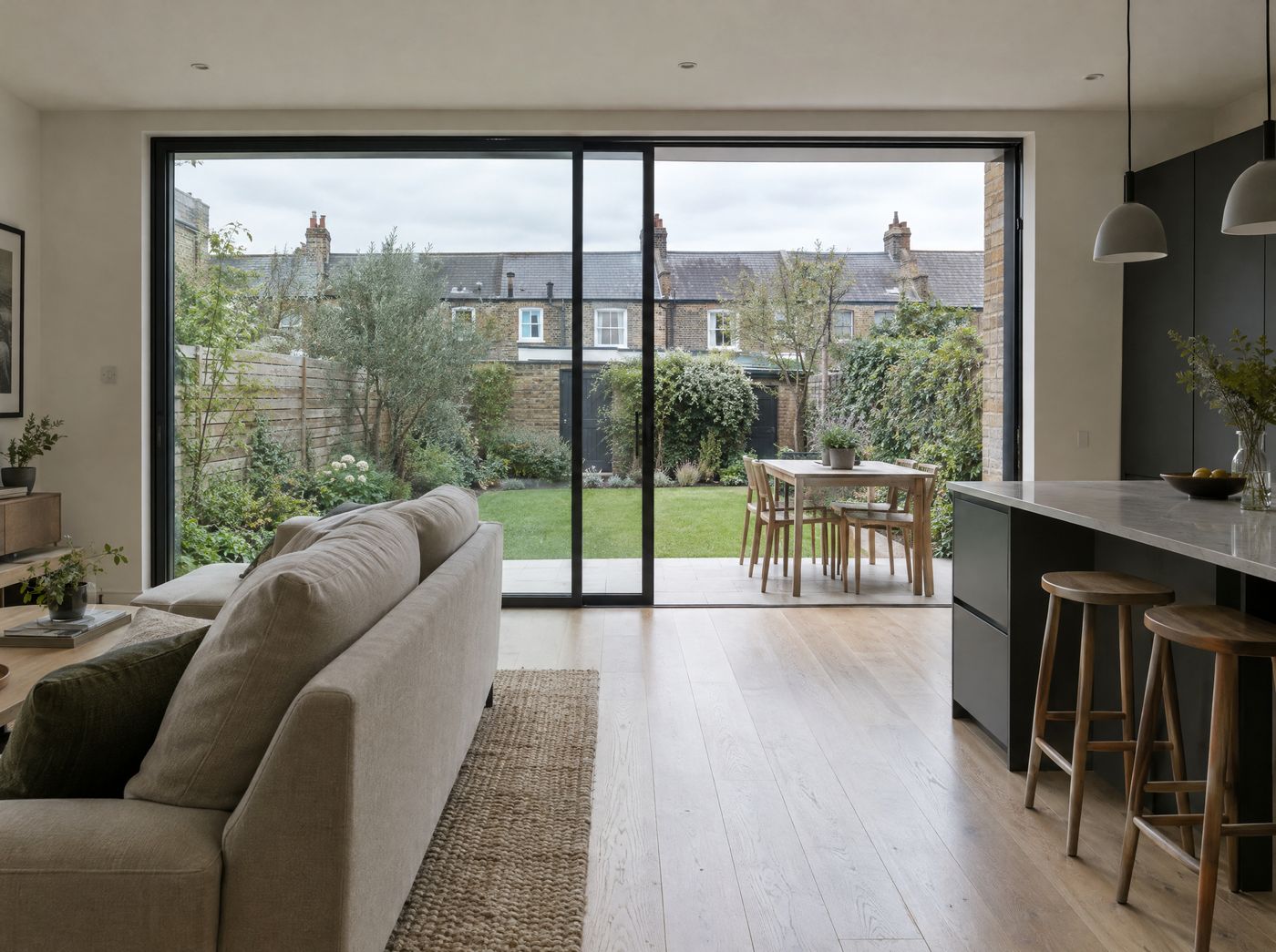 Two-panel slim black sliding door half open from a living room to the garden