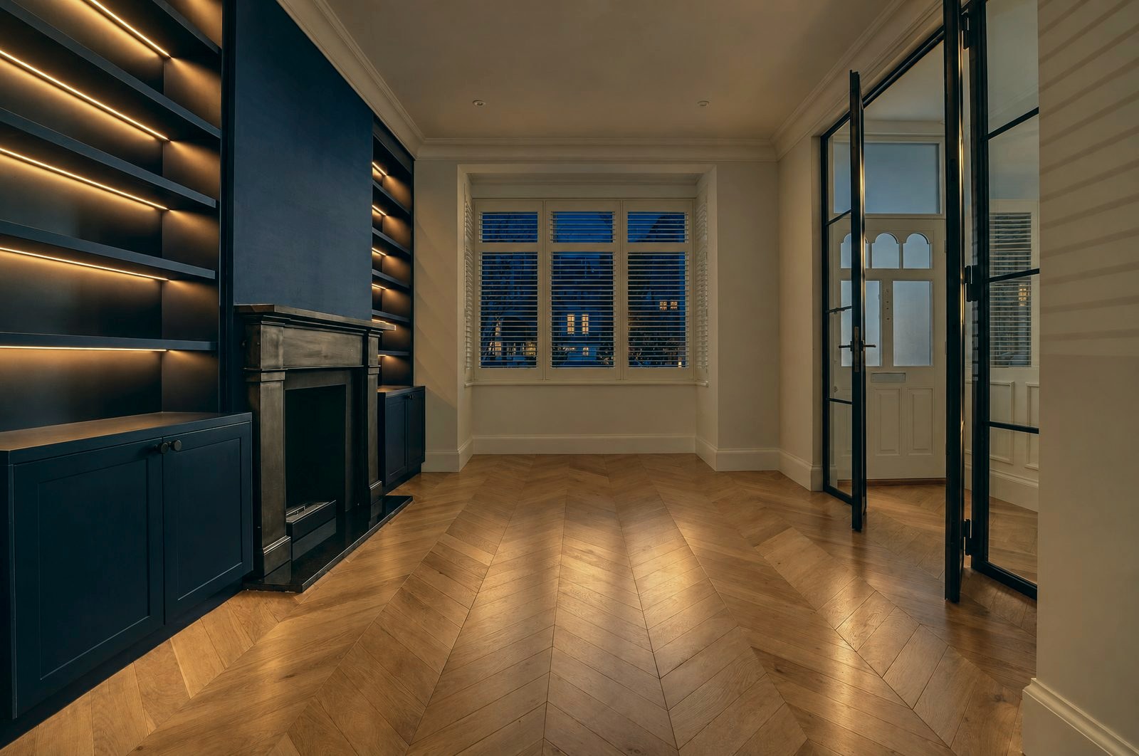Navy library with a bay window and open steel French doors