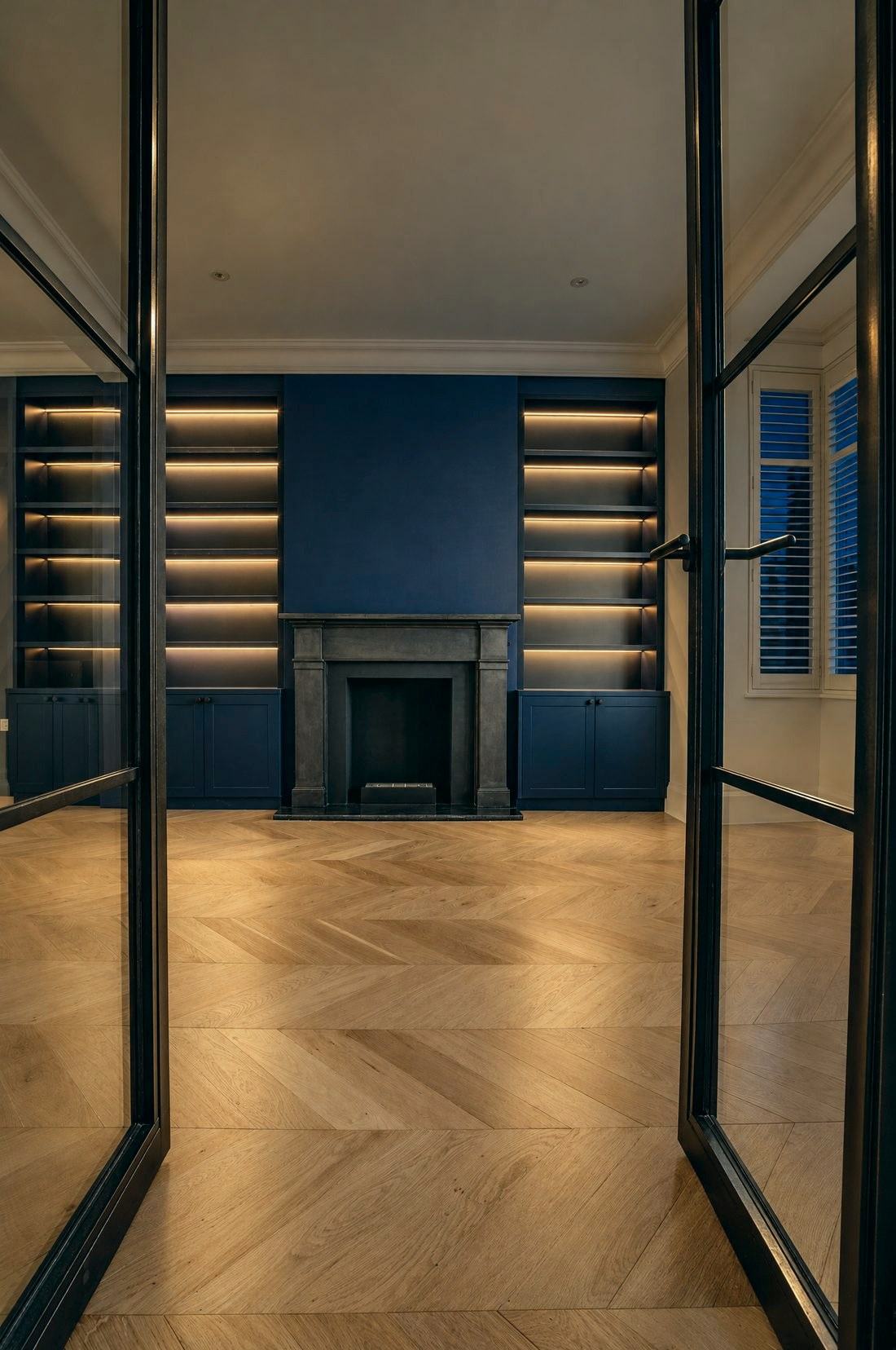 Open black steel French doors into a navy library