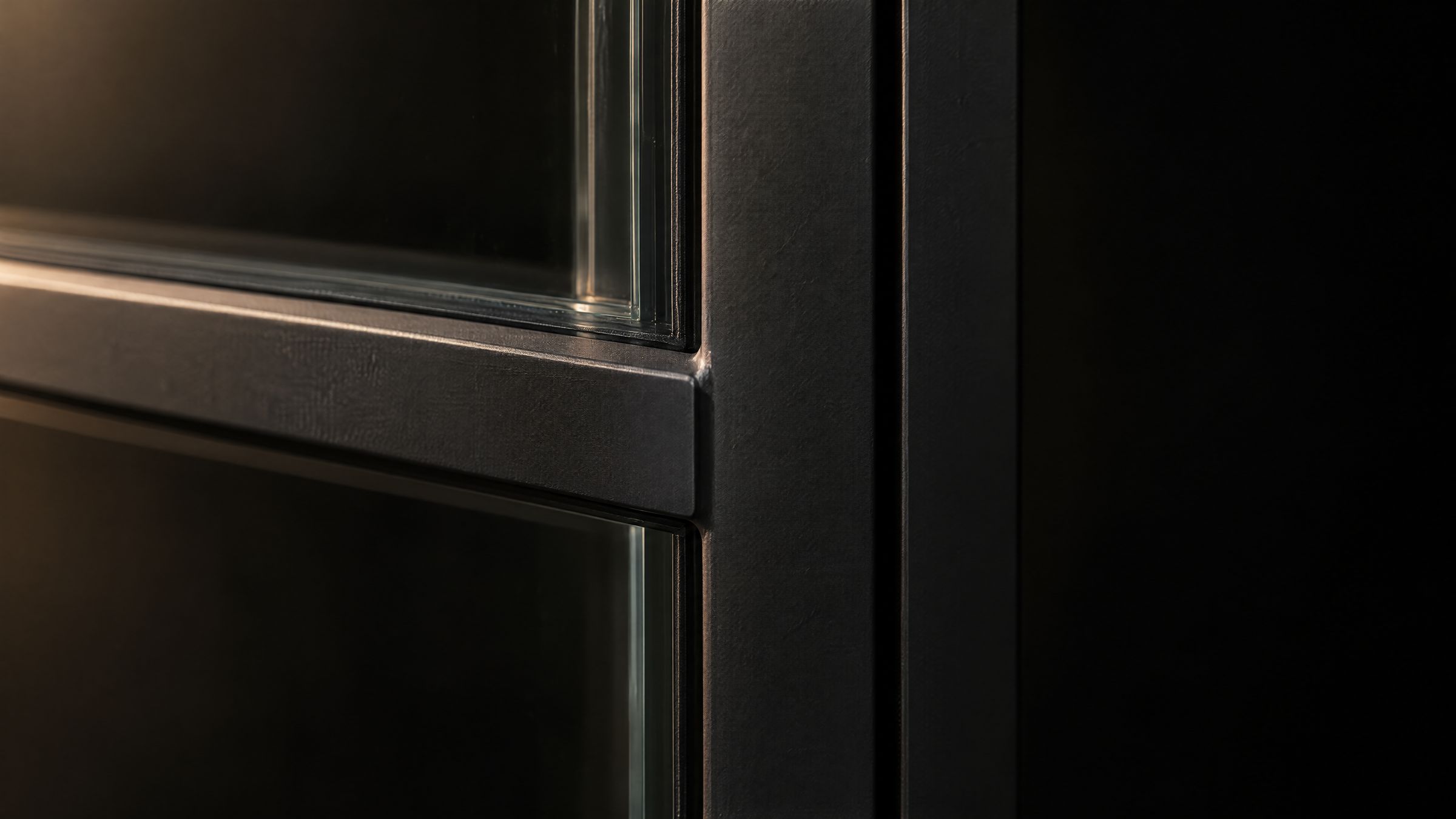 Close-up of a black steel glazing bar meeting the frame